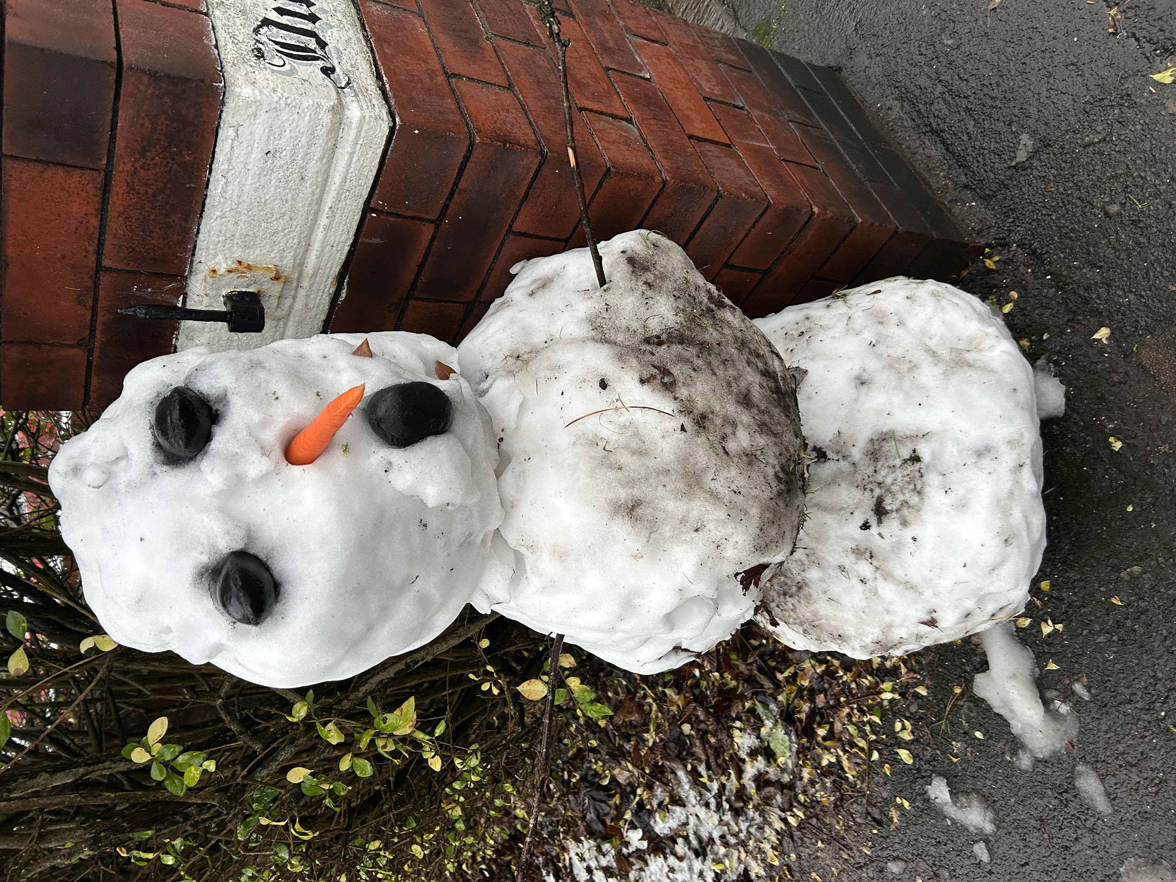 Photo of a snow person at the end of an 
		alleyway, the snow person is around 1.5m tall and has black objects for eyes and mouth; CC-BY-NC